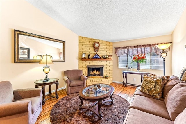 living room with a textured ceiling, light hardwood / wood-style flooring, lofted ceiling, and a fireplace