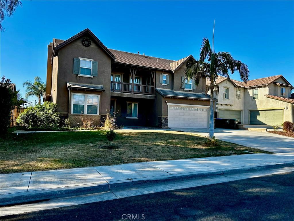 view of front of property featuring a balcony, a garage, and a front yard