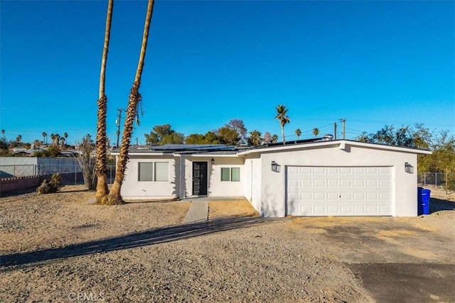 view of front of home with solar panels, fence, an attached garage, and stucco siding