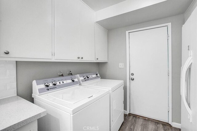 laundry room with dark hardwood / wood-style flooring, washer and dryer, and cabinets