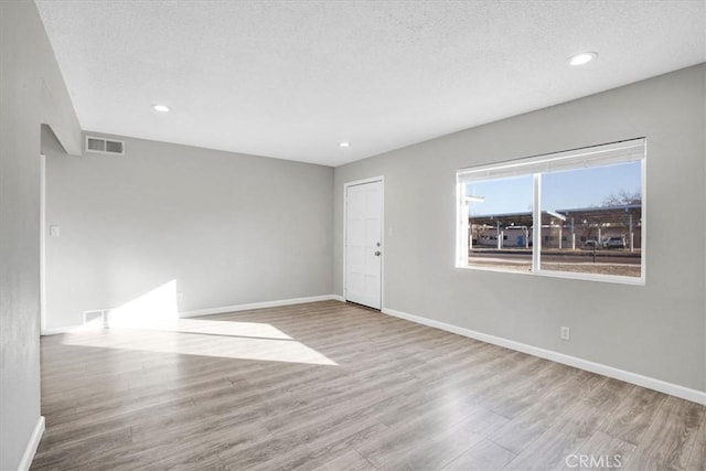 empty room with light hardwood / wood-style floors and a textured ceiling