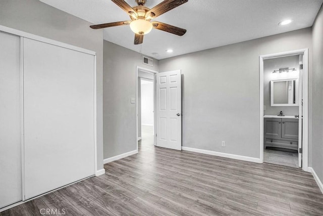 unfurnished bedroom with baseboards, a closet, visible vents, and wood finished floors