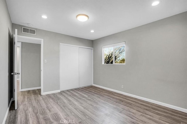 unfurnished bedroom featuring recessed lighting, a closet, visible vents, wood finished floors, and baseboards