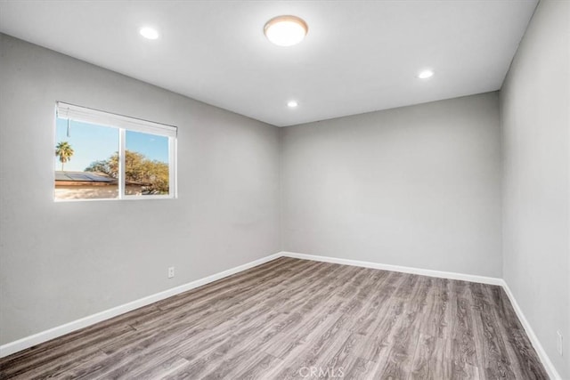 empty room with recessed lighting, wood finished floors, and baseboards