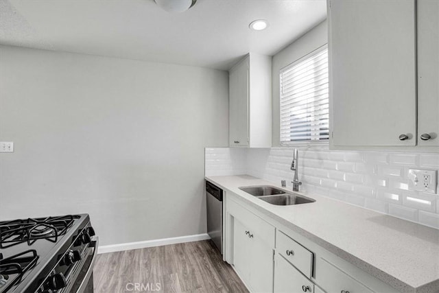 kitchen with tasteful backsplash, sink, light hardwood / wood-style flooring, appliances with stainless steel finishes, and white cabinets