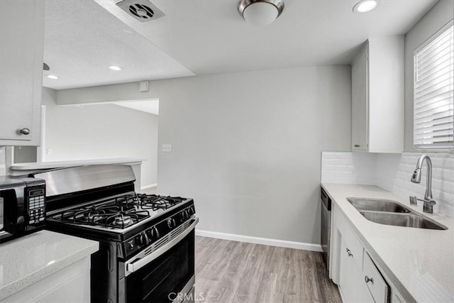 kitchen with light hardwood / wood-style floors, sink, white cabinetry, and stainless steel appliances