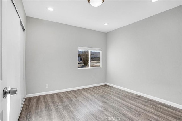 spare room featuring baseboards, wood finished floors, and recessed lighting