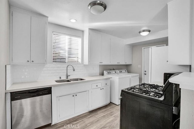 kitchen with light wood finished floors, dishwasher, washing machine and clothes dryer, white cabinetry, and a sink