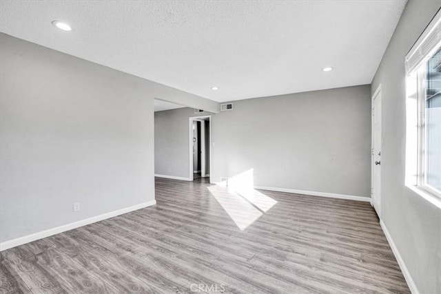 empty room with recessed lighting, visible vents, a textured ceiling, wood finished floors, and baseboards