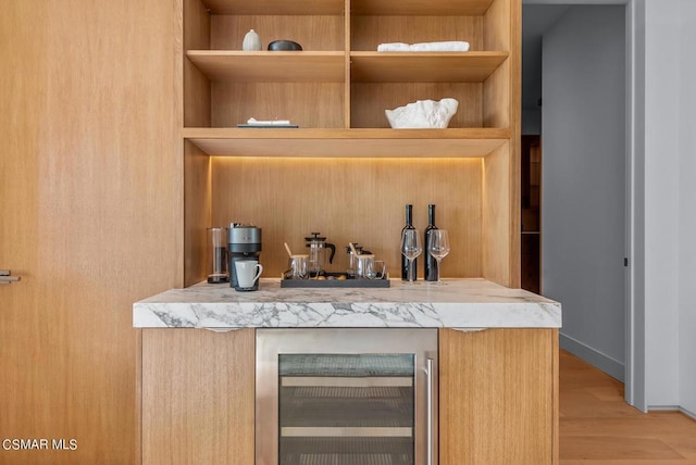 bar with light wood-type flooring, light brown cabinetry, and wine cooler