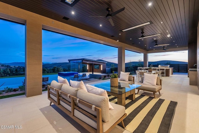 patio terrace at dusk featuring ceiling fan, an outdoor living space, and a mountain view