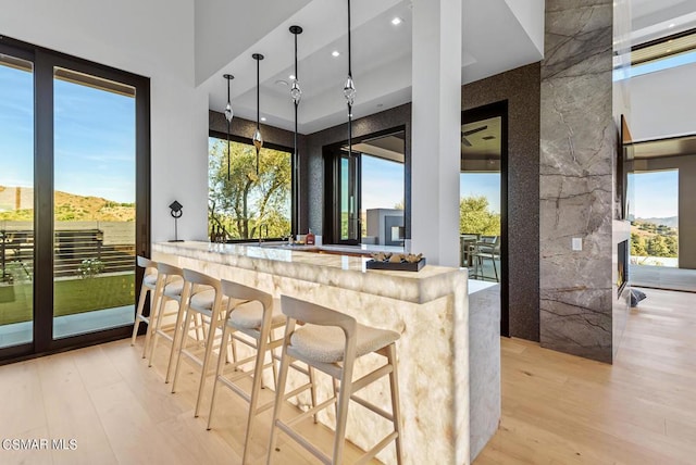 kitchen featuring a mountain view, a breakfast bar, a large fireplace, and light hardwood / wood-style flooring