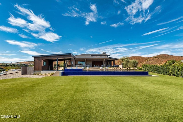 back of house with a mountain view and a yard