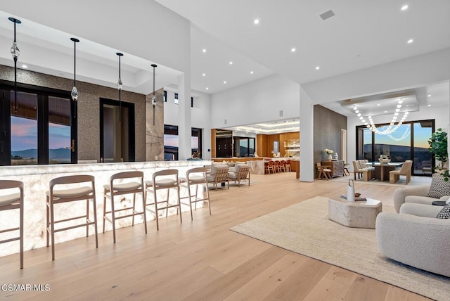 living room featuring a towering ceiling, a chandelier, and light hardwood / wood-style floors