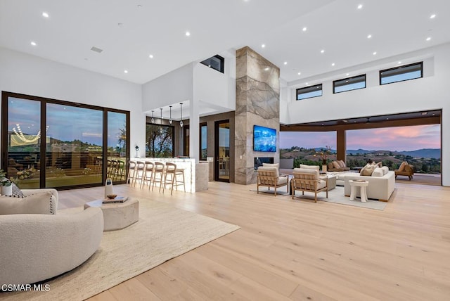 living room with a premium fireplace, a high ceiling, and light hardwood / wood-style flooring