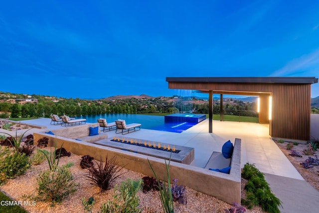 view of swimming pool with an in ground hot tub, a water and mountain view, a fire pit, and a patio