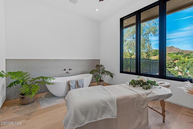 bathroom with a tub to relax in and hardwood / wood-style floors