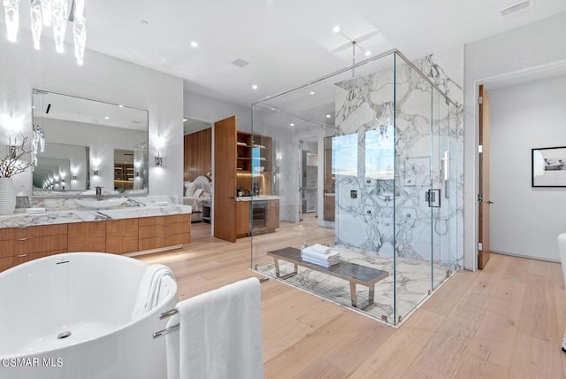 bathroom featuring hardwood / wood-style floors, vanity, and plus walk in shower