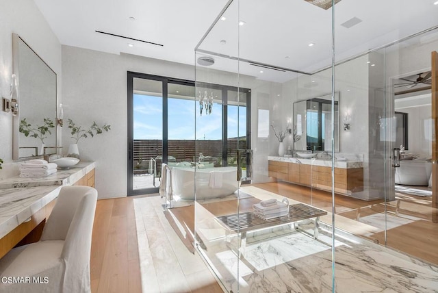 bathroom featuring plus walk in shower, ceiling fan with notable chandelier, wood-type flooring, and vanity