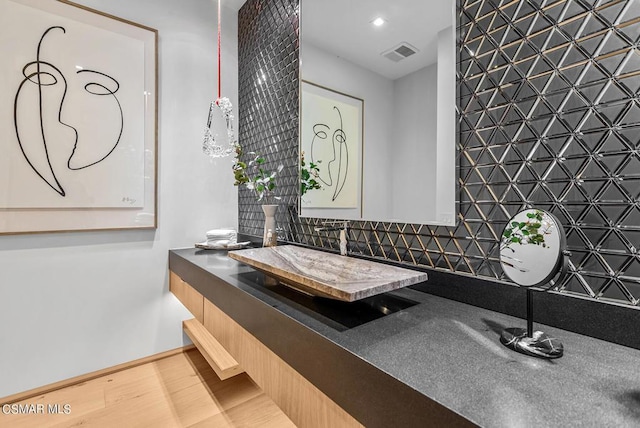 bathroom featuring wood-type flooring, vanity, and tasteful backsplash