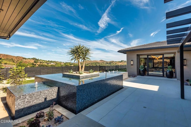 view of patio / terrace featuring a mountain view and pool water feature