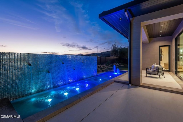 patio terrace at dusk with a pool and pool water feature