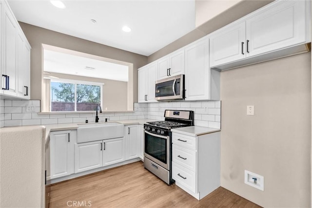 kitchen featuring stainless steel appliances, decorative backsplash, white cabinets, and sink