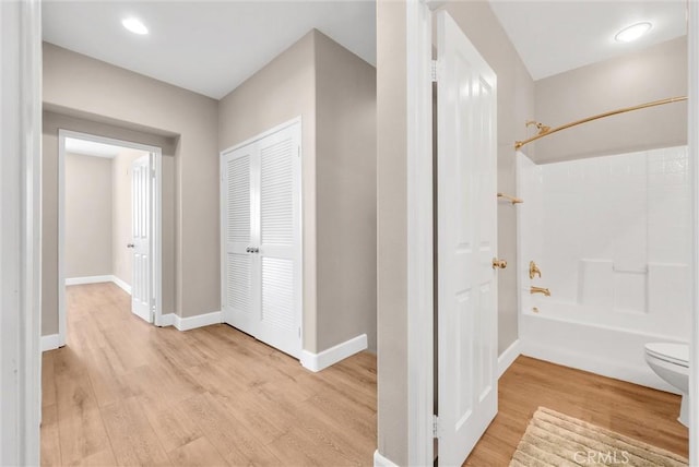 bathroom featuring hardwood / wood-style floors, bathing tub / shower combination, and toilet