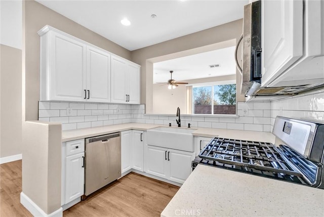 kitchen with white cabinetry, light hardwood / wood-style floors, sink, tasteful backsplash, and appliances with stainless steel finishes