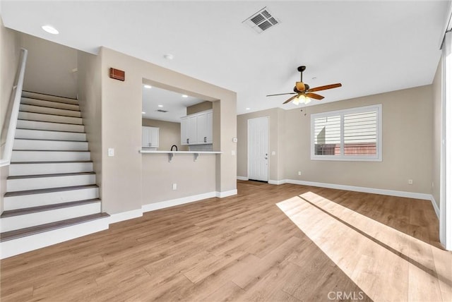 unfurnished living room featuring ceiling fan and light hardwood / wood-style flooring