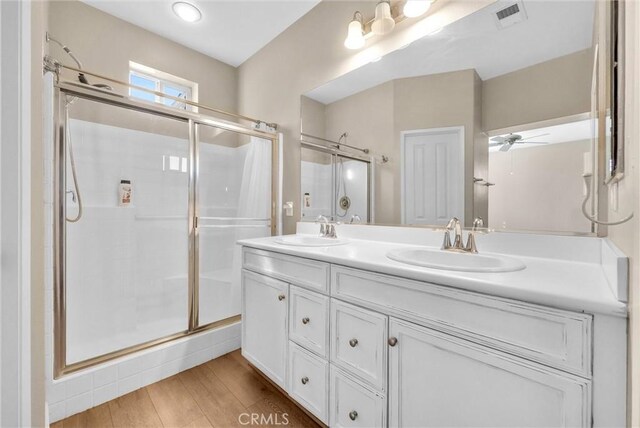 bathroom featuring ceiling fan, hardwood / wood-style floors, a shower with shower door, and vanity