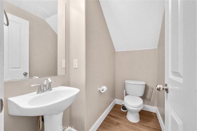 bathroom featuring sink, hardwood / wood-style floors, toilet, and lofted ceiling