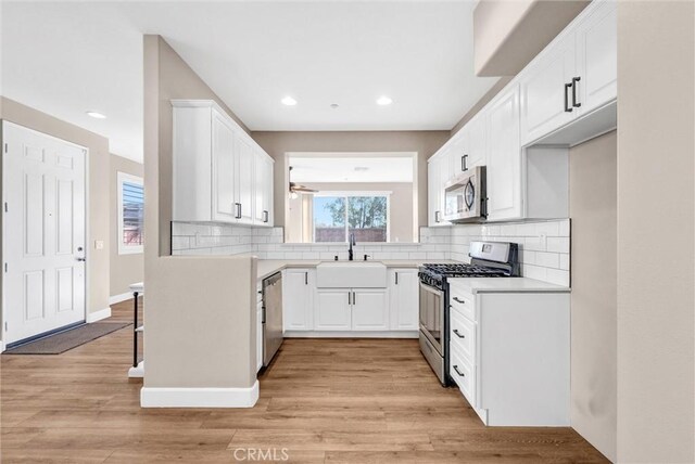 kitchen featuring stainless steel appliances, light hardwood / wood-style flooring, white cabinetry, and sink