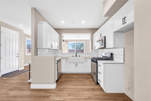 kitchen featuring appliances with stainless steel finishes, decorative backsplash, light hardwood / wood-style floors, sink, and white cabinetry