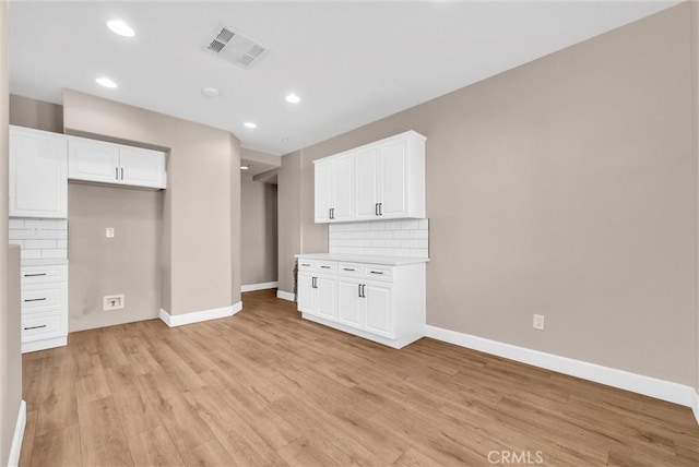 interior space with white cabinetry, tasteful backsplash, and light hardwood / wood-style floors