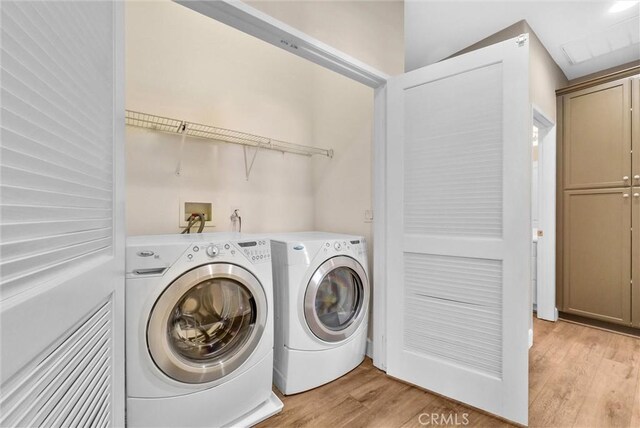 clothes washing area featuring separate washer and dryer and light hardwood / wood-style flooring