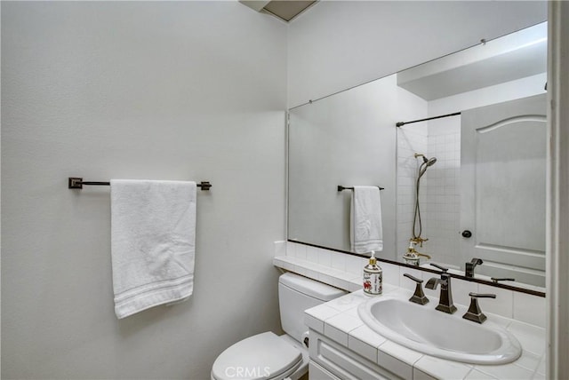 bathroom featuring a shower, vanity, and toilet