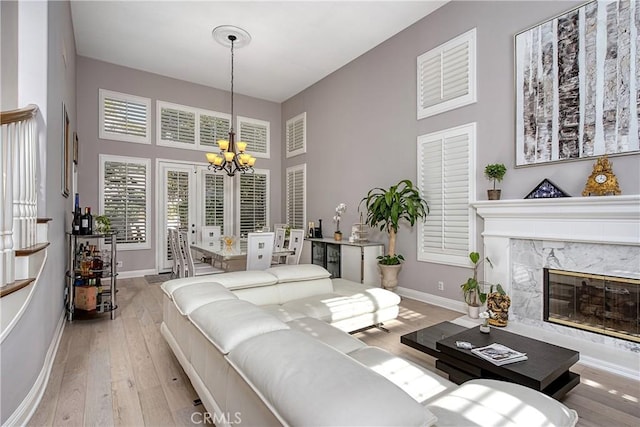 bedroom with a notable chandelier, a premium fireplace, and light wood-type flooring