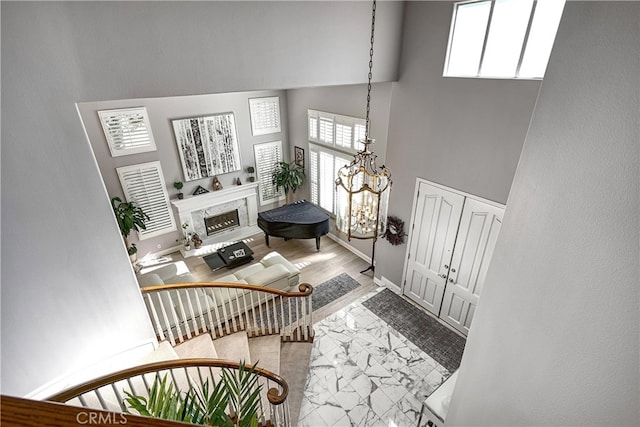 foyer entrance with an inviting chandelier, a towering ceiling, and a fireplace