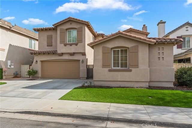 mediterranean / spanish house featuring a garage and a front lawn