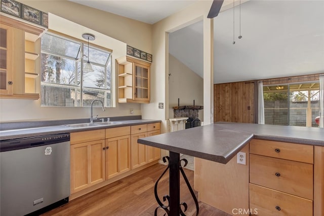 kitchen with decorative light fixtures, a kitchen bar, light brown cabinets, sink, and stainless steel dishwasher