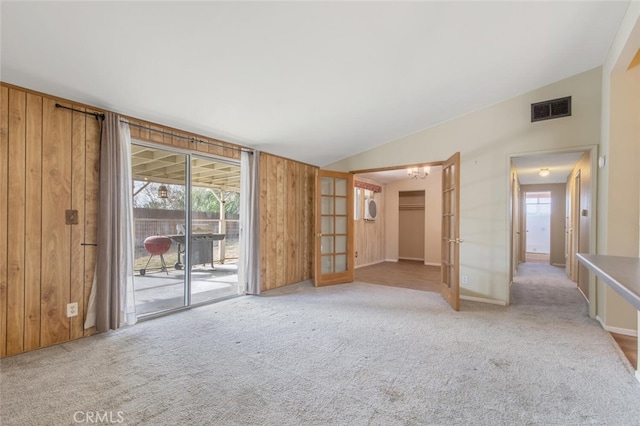 interior space featuring french doors, vaulted ceiling, wood walls, and a notable chandelier