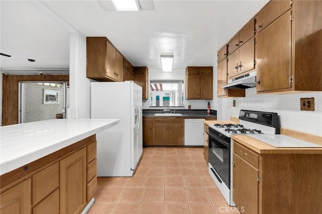 kitchen featuring light tile patterned floors, decorative backsplash, sink, and white appliances