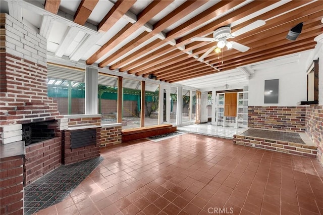 sunroom / solarium with ceiling fan, a wealth of natural light, beamed ceiling, and a fireplace