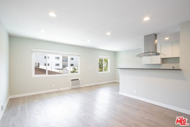 unfurnished living room with light hardwood / wood-style flooring and a wall mounted AC