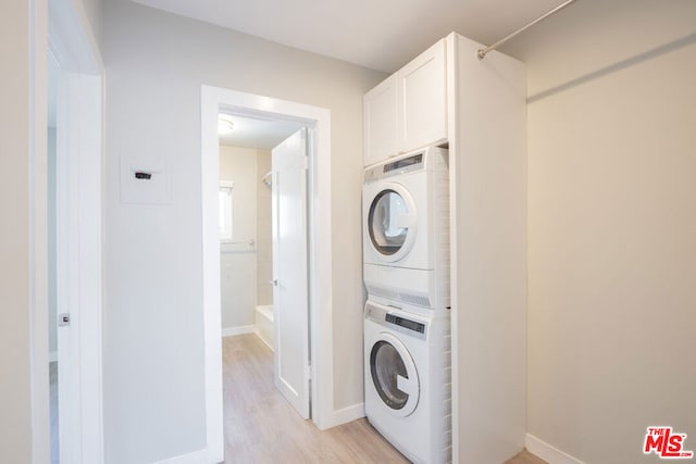 laundry room featuring stacked washer and clothes dryer and light hardwood / wood-style flooring