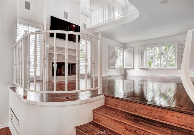 stairs featuring a high ceiling, hardwood / wood-style floors, and a fireplace