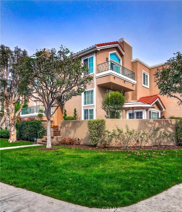 mediterranean / spanish-style house featuring a balcony and a front yard