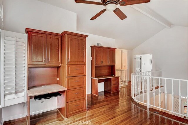 office space with hardwood / wood-style flooring, ceiling fan, built in desk, and vaulted ceiling with beams