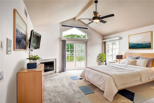 carpeted bedroom featuring access to exterior, vaulted ceiling with beams, a tile fireplace, and ceiling fan